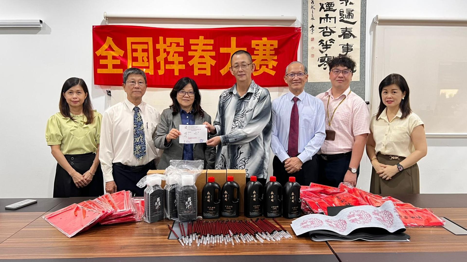 奕中校长张贵娟博士，陈永兴主任（右二）接受挥春大赛书法用品