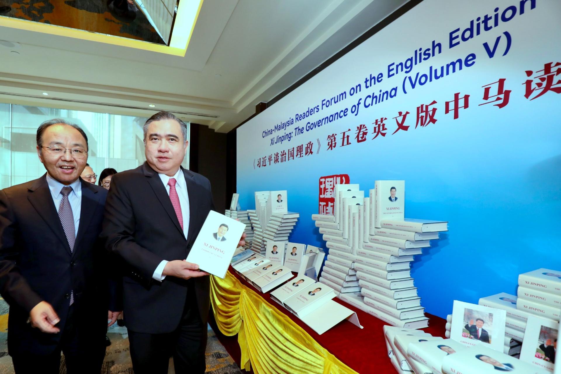陆兆福（右起）与欧阳玉靖翻阅《习近平谈治国理政》书籍。