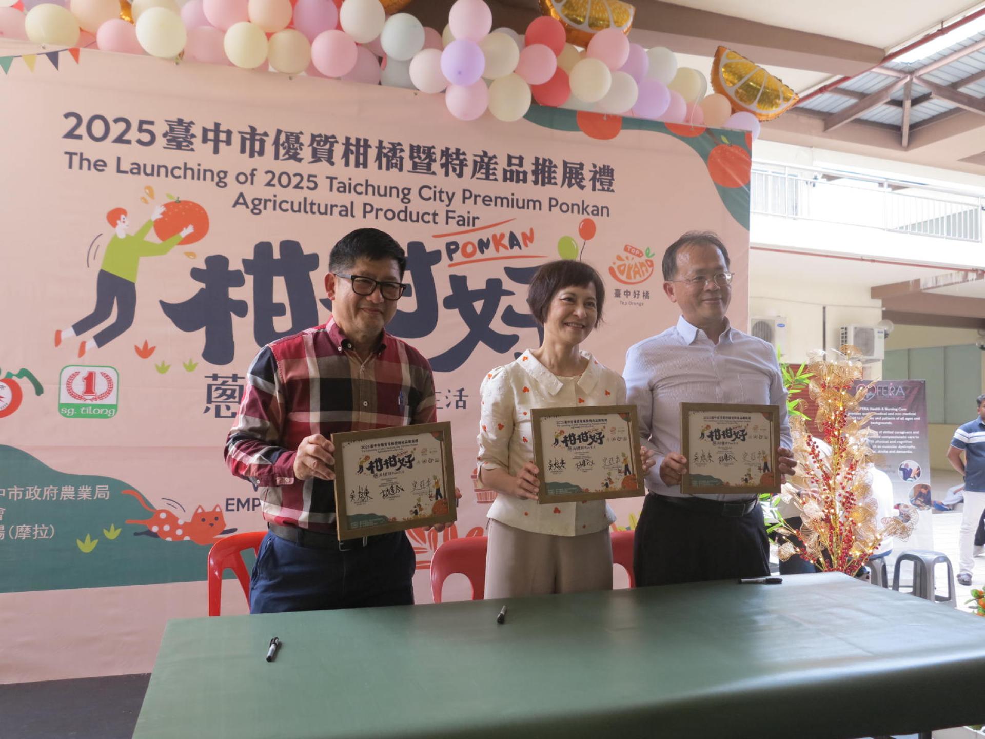 驻汶莱台北经济文化代表处史代表亚平（中）与第一百货集团董事经理林建成及丰原区农会推广主任吴炫东在推展匾牌签名后合影