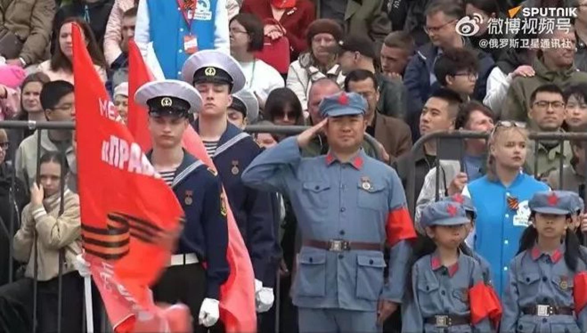 中国小朋友们穿着灰色制服、左胳膊戴红袖章参与活动。
