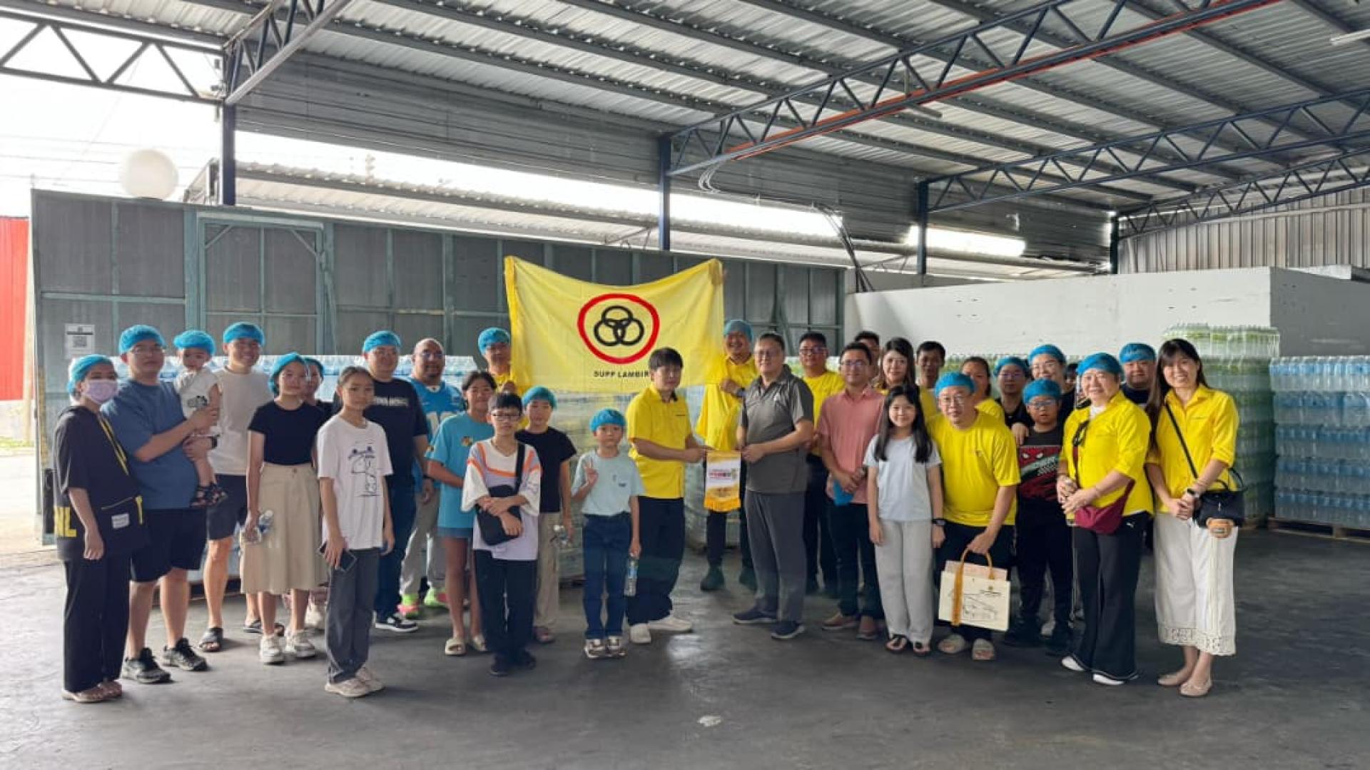 参与者参观矿泉水厂后大合影。图为人联党兰卑尔支部主席王智义赠送锦旗给晨霧矿泉水厂。