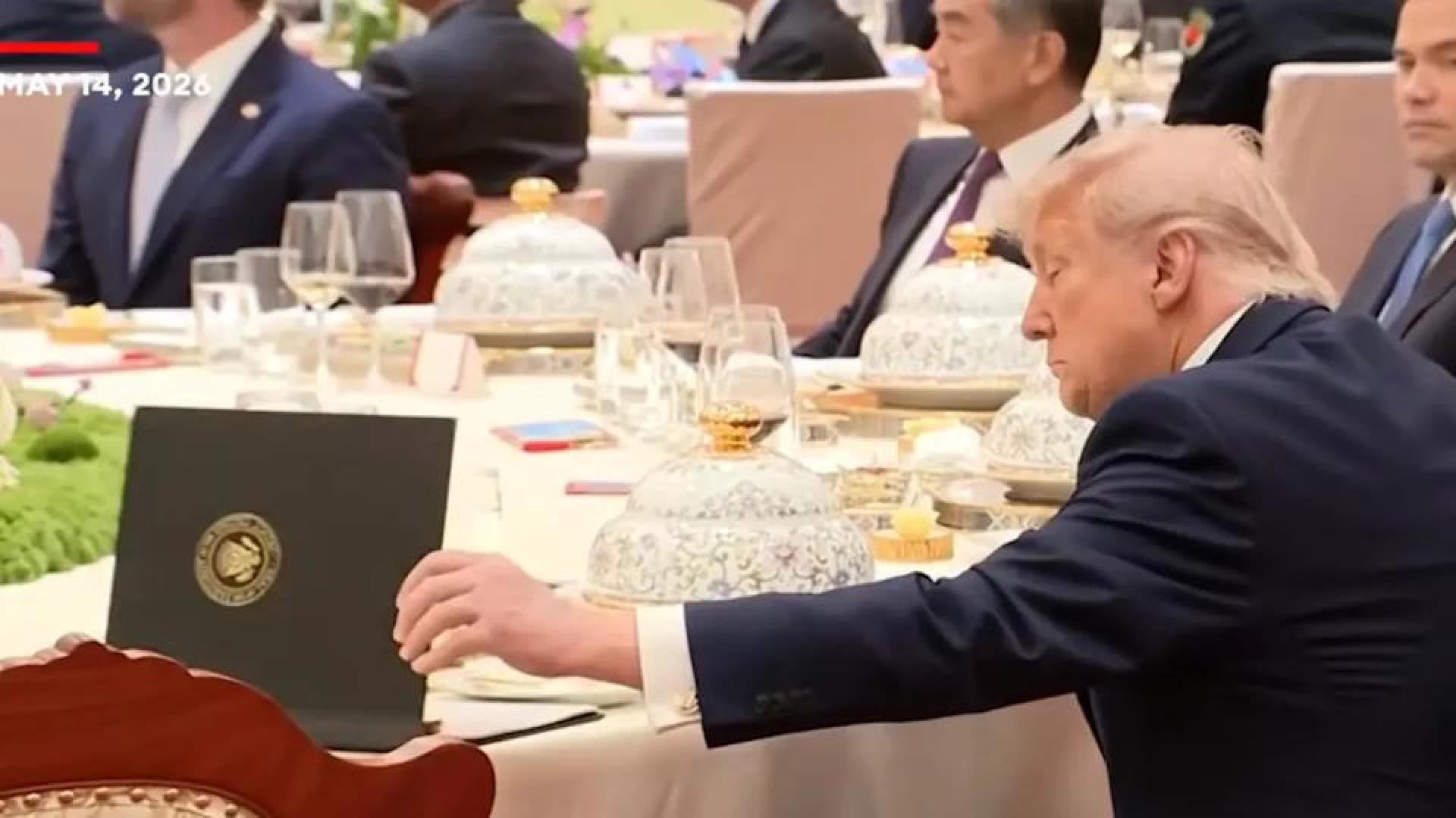 特朗普快速翻阅一本黑色资料夹后又将其阖上。