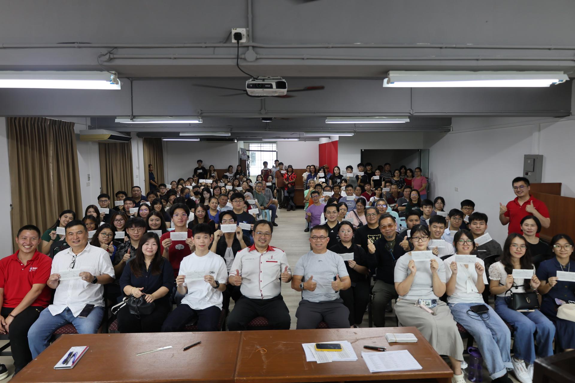 全体受惠的学子及家人开心展示奖励金支票，与砂行动党实旦宾区国会议员张健仁（前左5）及团队们合影。