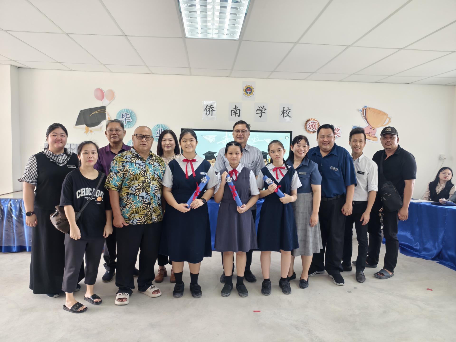 3名2024/2025学年第一届小六毕业生在家长的陪同下领取毕业证书，与董事部成员、校长、副校长合影。
