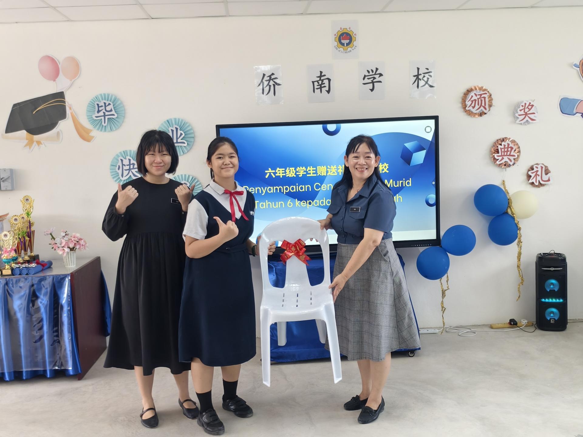六年级学生赠送礼物给母校。右为校长许琳瑛接收。