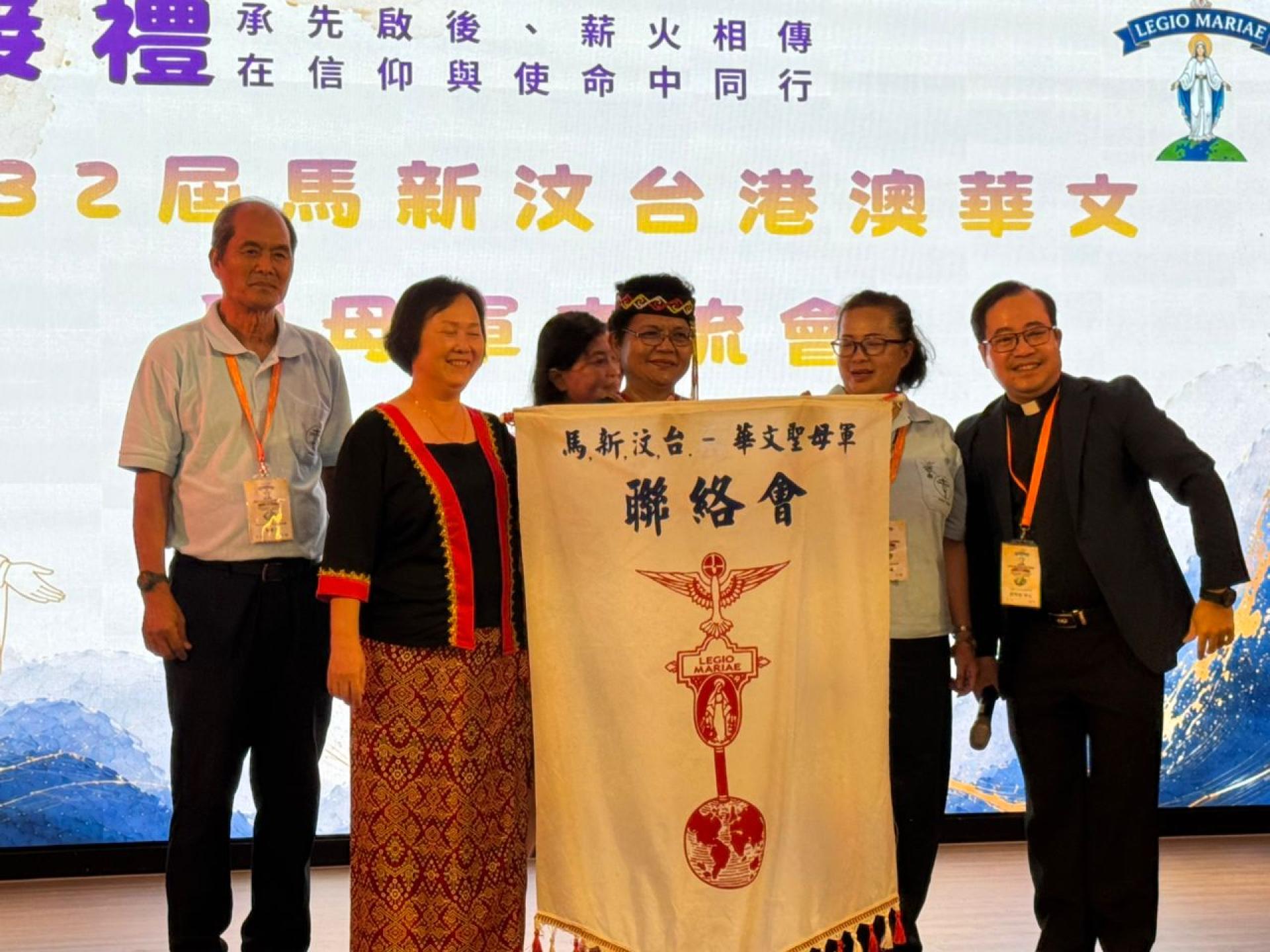 移交圣母军交流会旗帜。（右一）台中黄明强神父、（右二）台中普天之后督察区团团长罗文琪移交(右三）古晋诸宠圣母区团团长欧月好及团委合影。