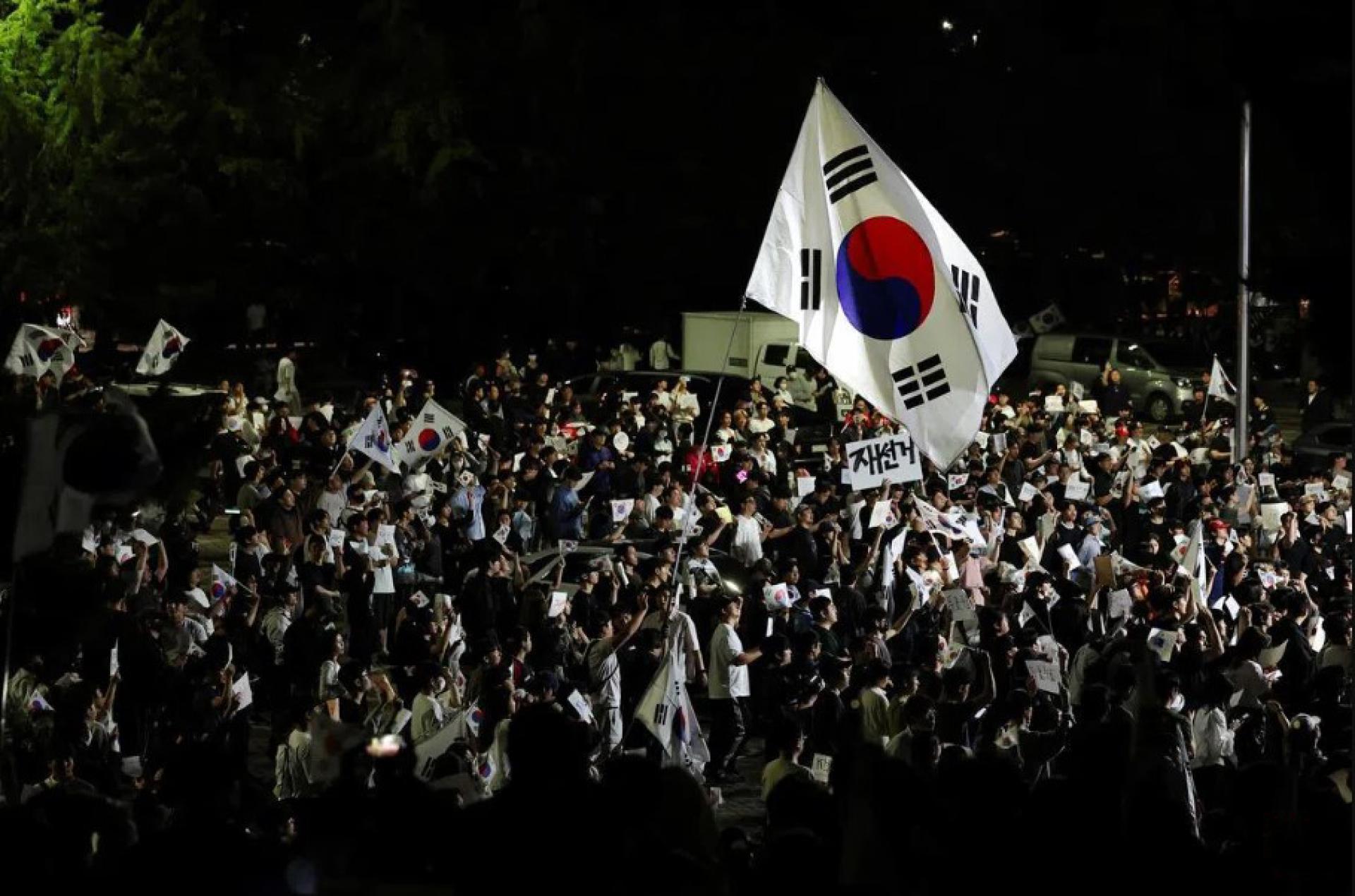 韩国大批示威者星期六（6月6日）聚集在首尔地方选举计票地点，继续抗议部分选区选票短缺问题。抗议人群挥舞巨大的韩国国旗，高呼“重新选举”。