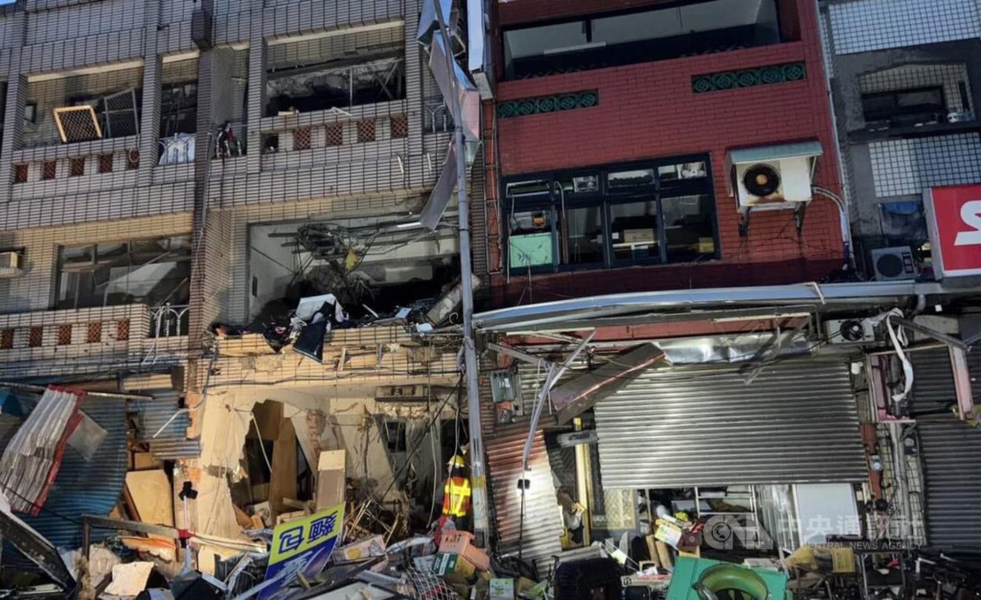 现场可见建物外墙及窗户严重毁损，道路满布砖块、铁皮及玻璃等碎片，多辆停放路旁车辆受波及。