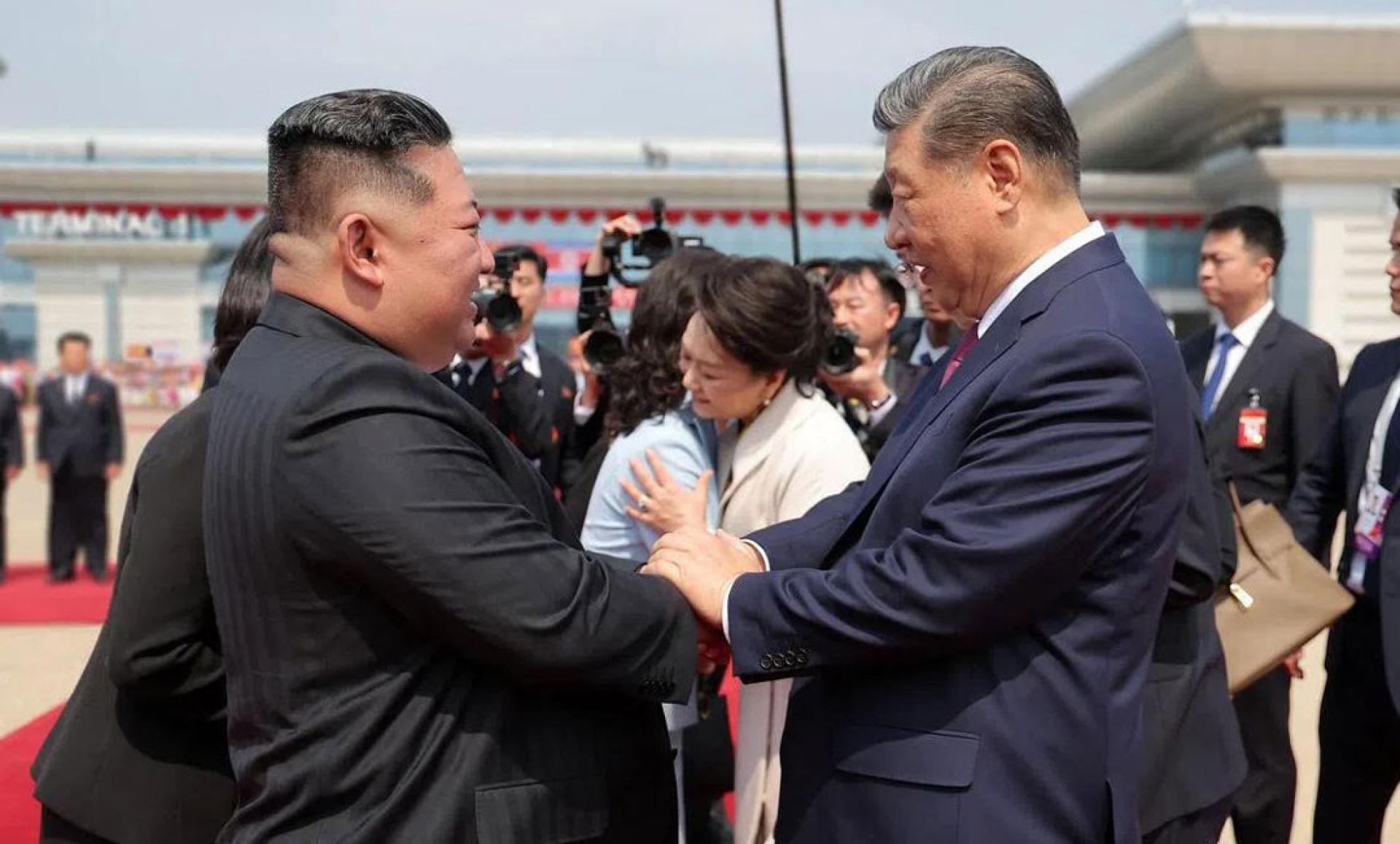 习近平（前排右）在平壤机场与金正恩（前排左）握手道别；习近平夫人彭丽媛（后排右）也与金正恩夫人李雪主（后排左）相拥。