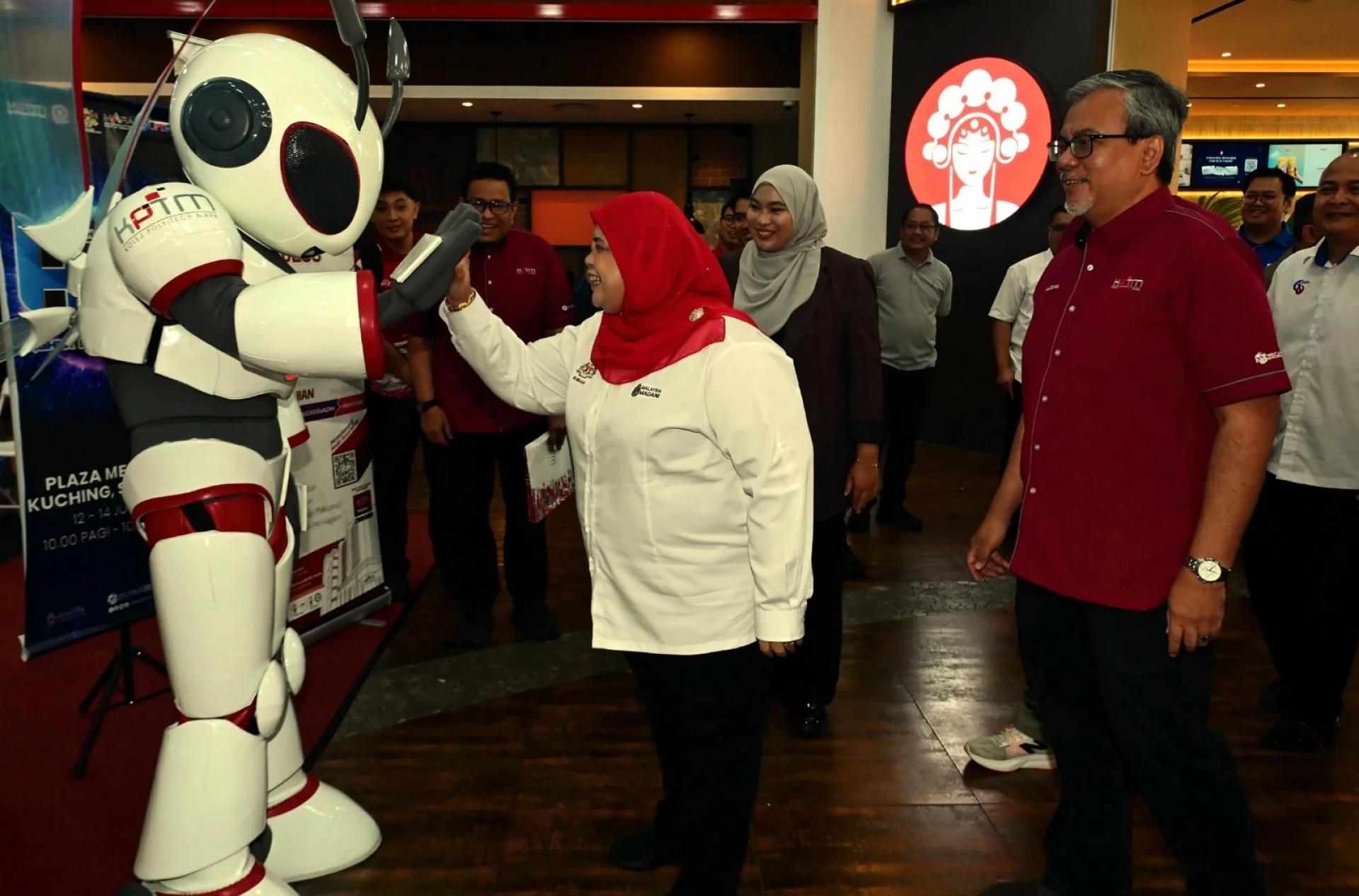 Rubiah (tengah) disambut oleh robot Nexel (kiri) sebaik tiba pada majlis pelancaran Karnival HITS Sarawak 2026, di sini, hari ini.