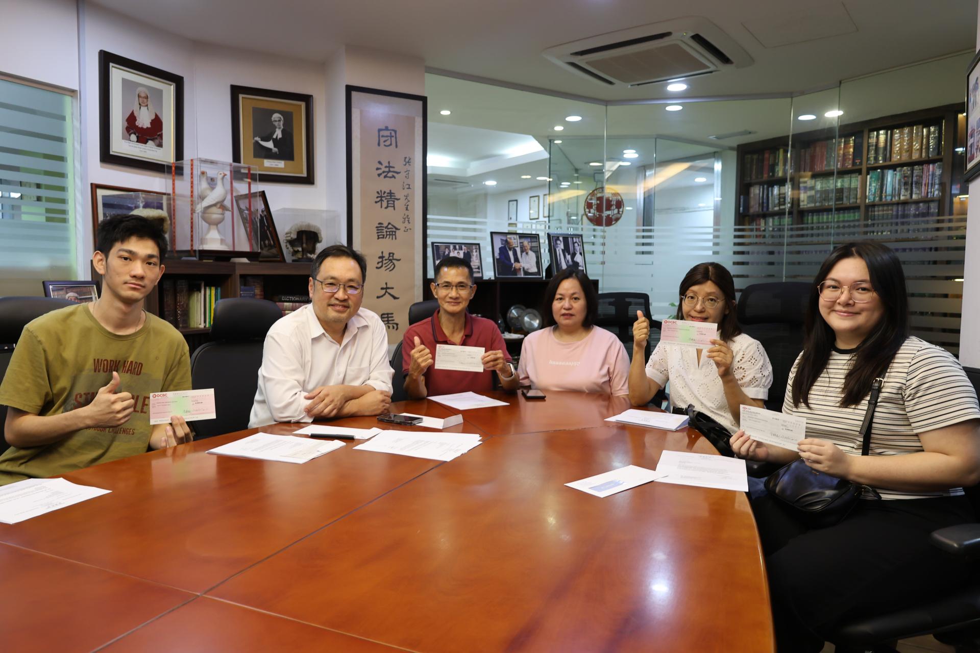 实旦宾区国会议员兼浮罗岸州议员张健仁（左2）与领取李氏基金会助学金支票的受惠学子及代领助学金支票的家属合影。