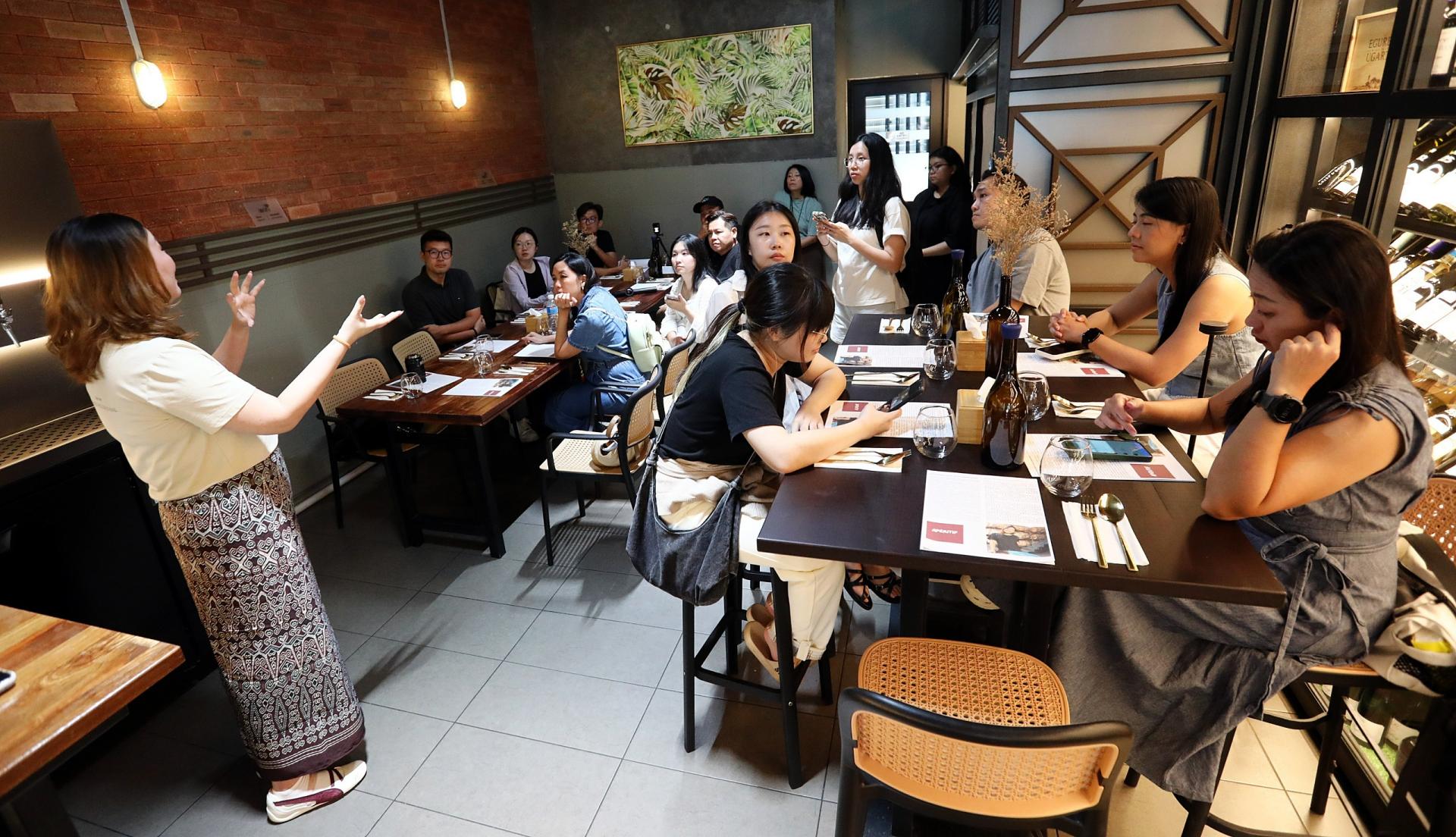 媒体考察团成员体验土酒品鉴活动，并搭配砂拉越特色美食，感受独特饮食文化魅力。