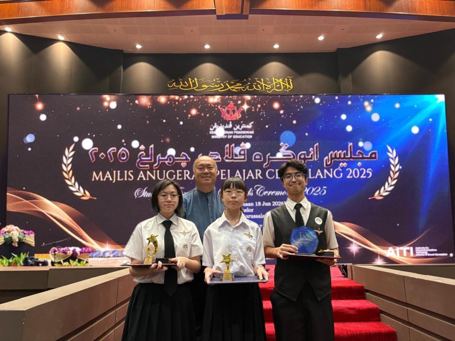三位获奖学生在颁奖台前与中正中学贾仁佑校长合影留念。左起依次为韩乐宣、陈薇恩、杨士民。