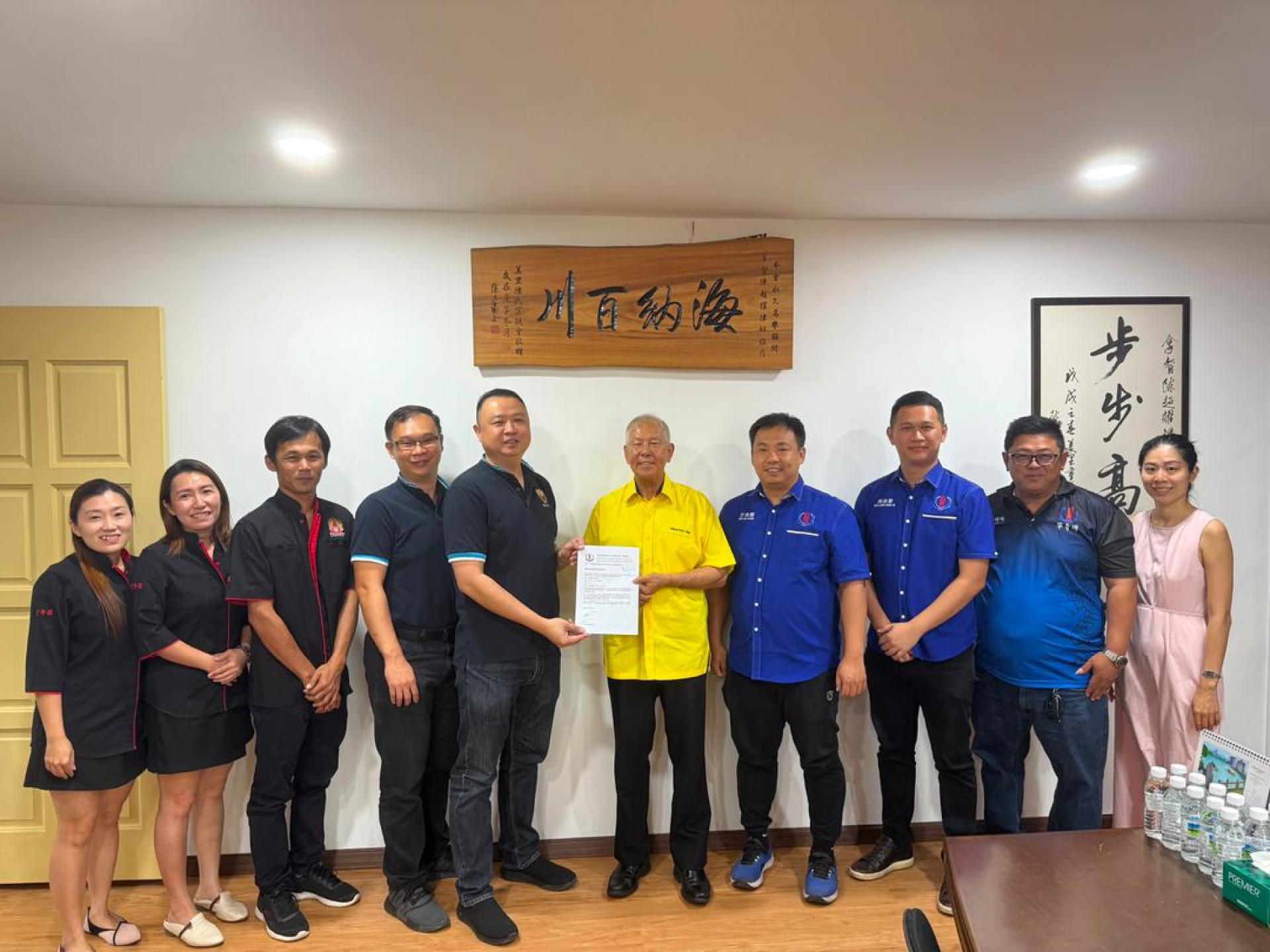 美里省华总青年团署理团长兼美里诏安会馆青年团团长许伟强（左5）移交邀请函予砂旅游部副部长拿督陈超耀。右4为美里省华总青年团团长许佳顺以及左3为美里潮州公会青年团团长吴洪庆。