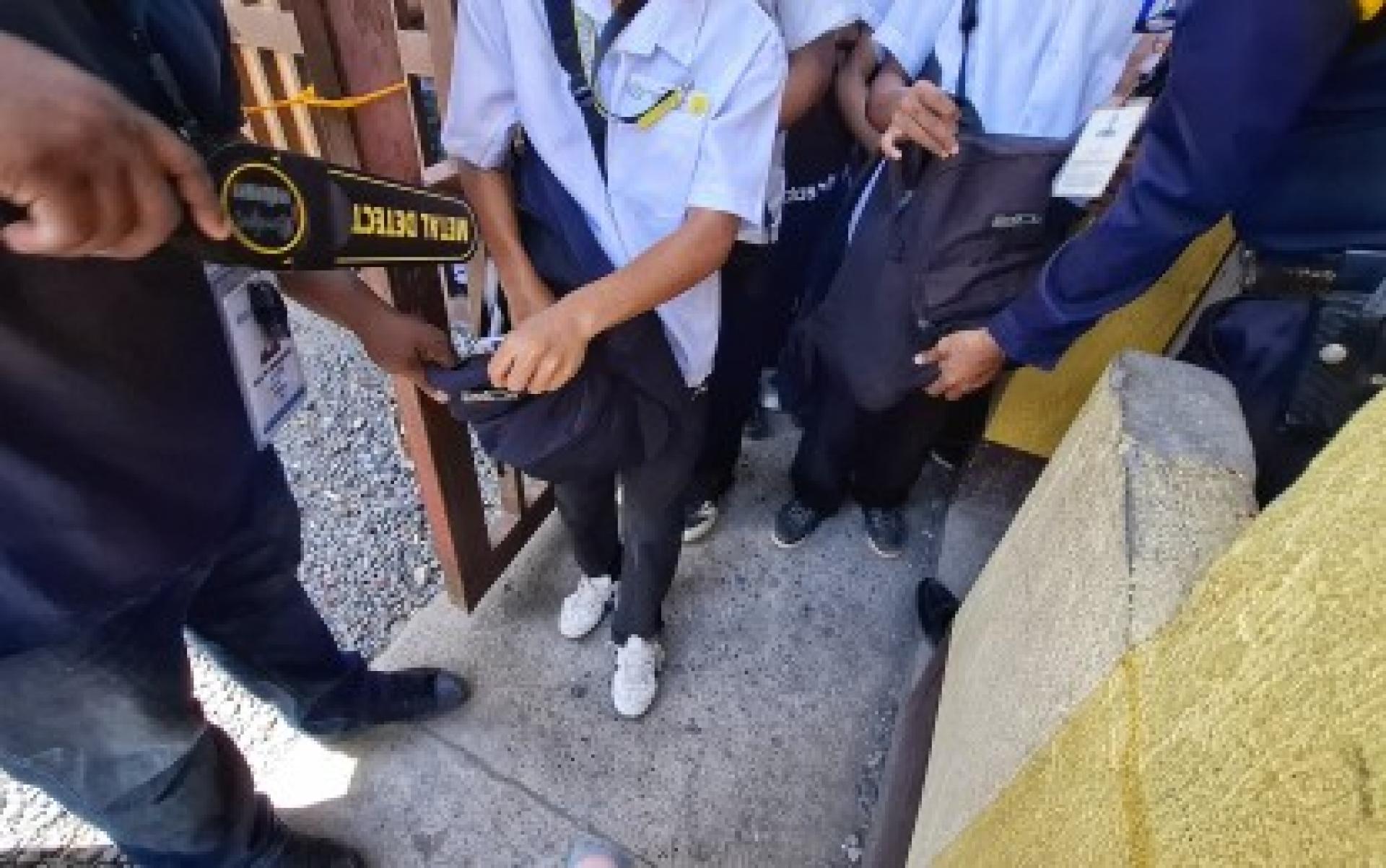 达沃市圣安娜国立中学保安人员于6月23日在校门口检查一名男学生的书包，加强校园安全防范措施。菲律宾多地学校近期提升安检等级，以保障师生安全。