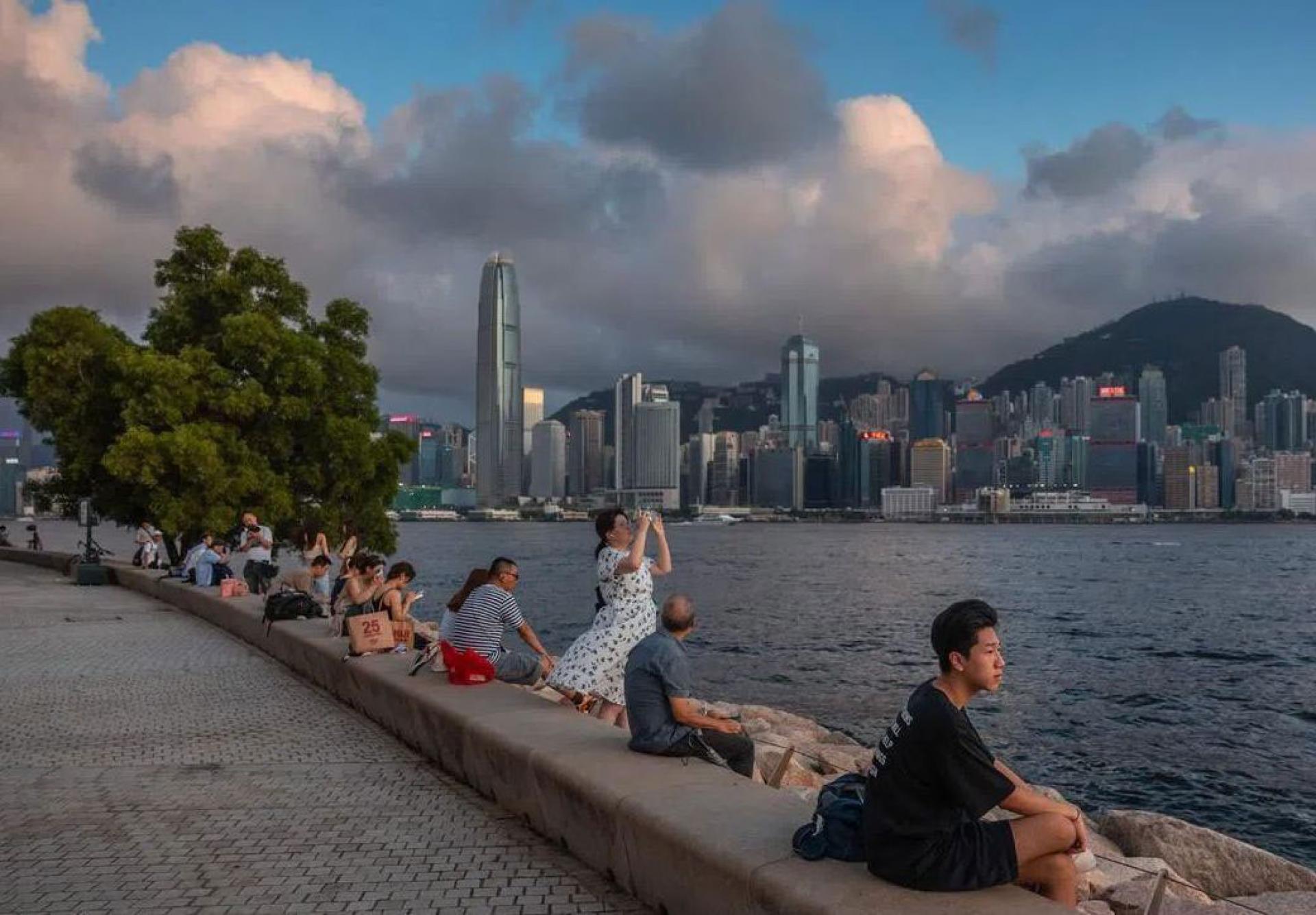 图为公众于6月23日坐在香港维多利亚港旁的滨海长廊上。