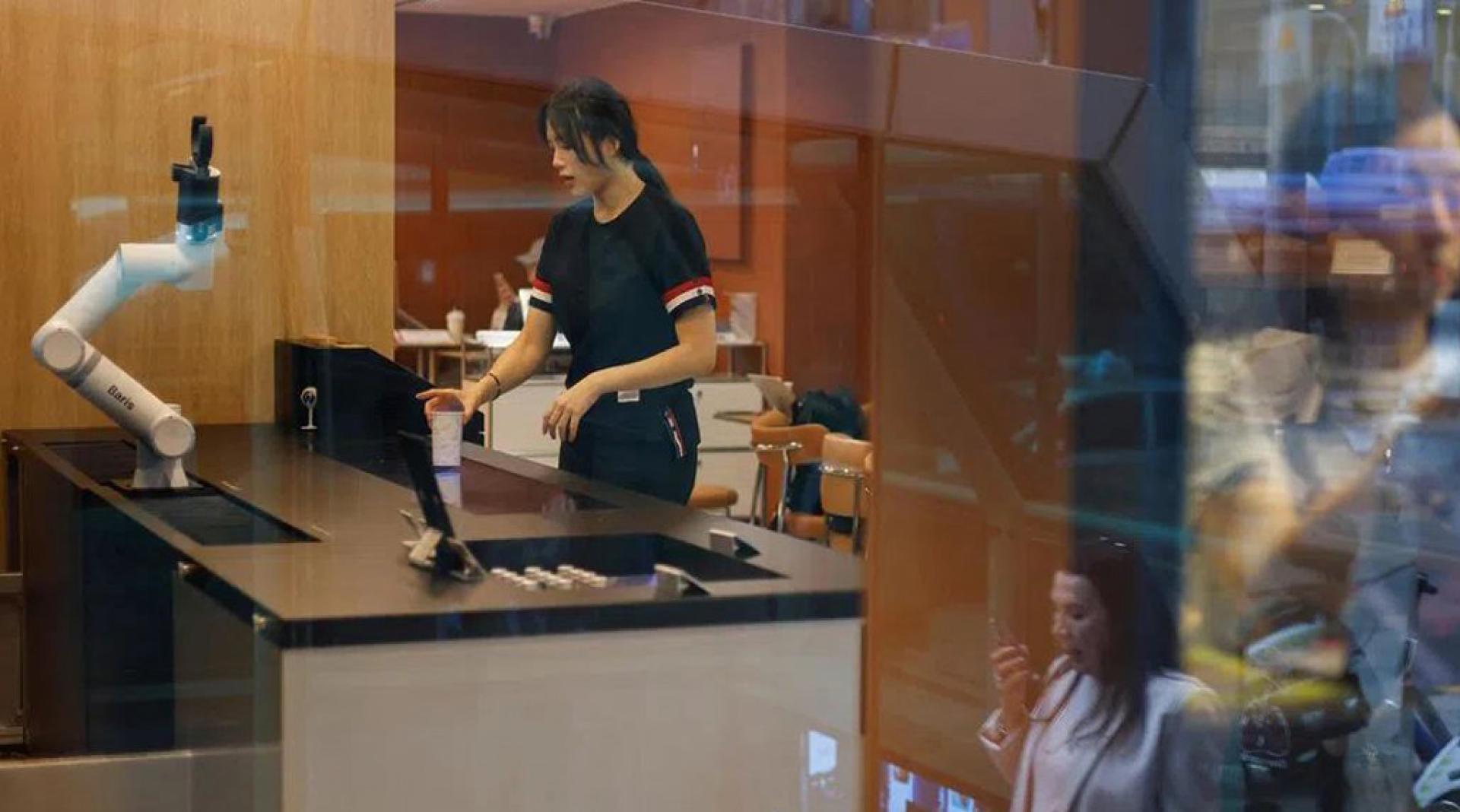 一名顾客在韩国首尔一家无人咖啡厅享用由机械臂制作的咖啡。