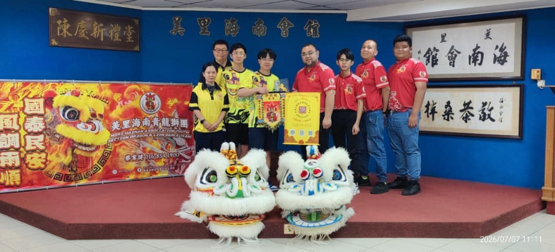 美里海南青龍狮团团长蔡常健（右4）与加拿大埃德蒙顿关圣宫龍狮团代表交换锦旗。