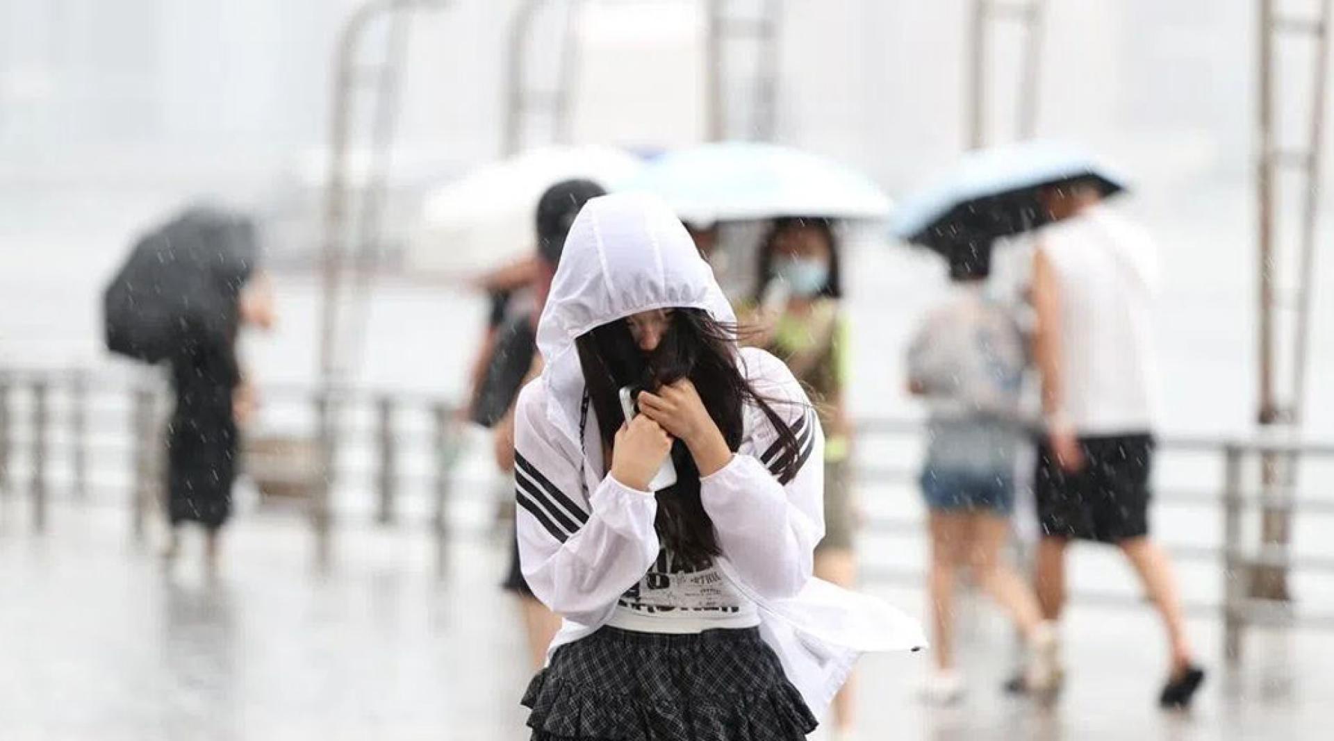 受台风“红霞”影响，香港市民在雨中出行。