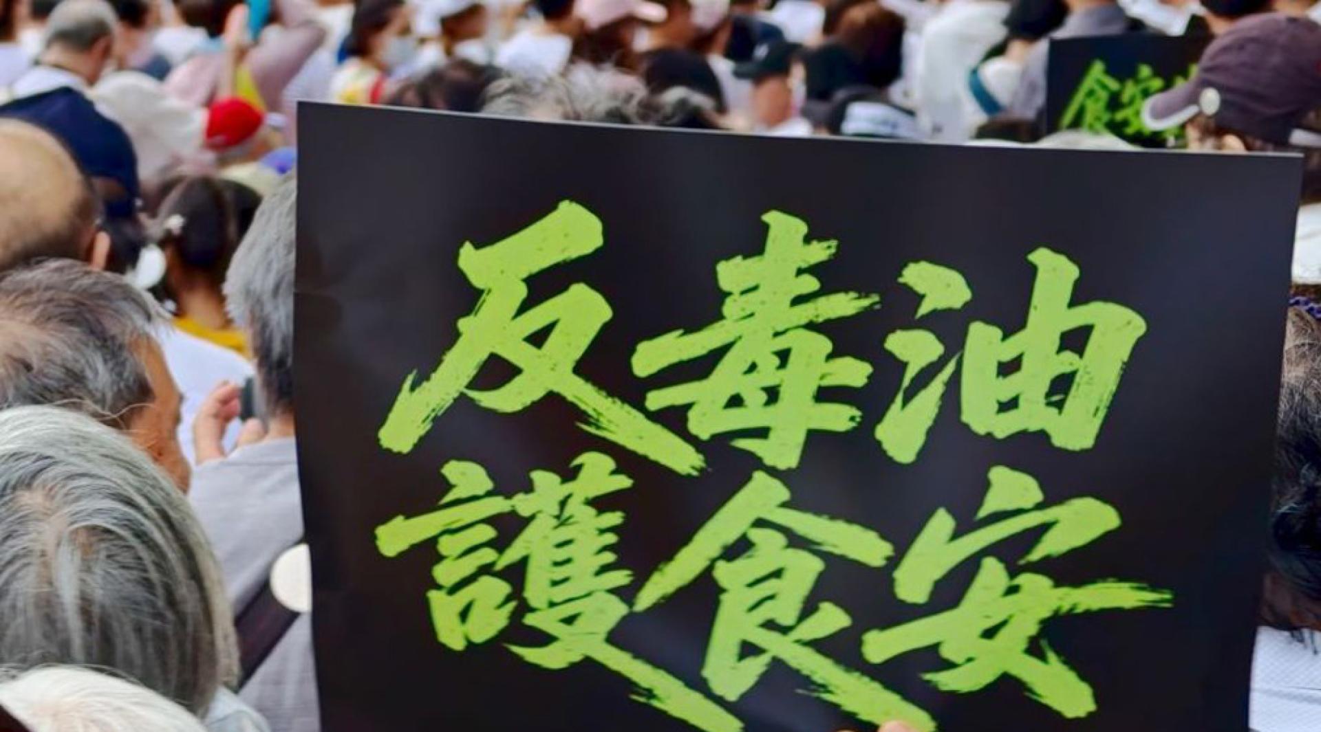 一名民众举着“反毒油，护食安”的标语表达抗议。