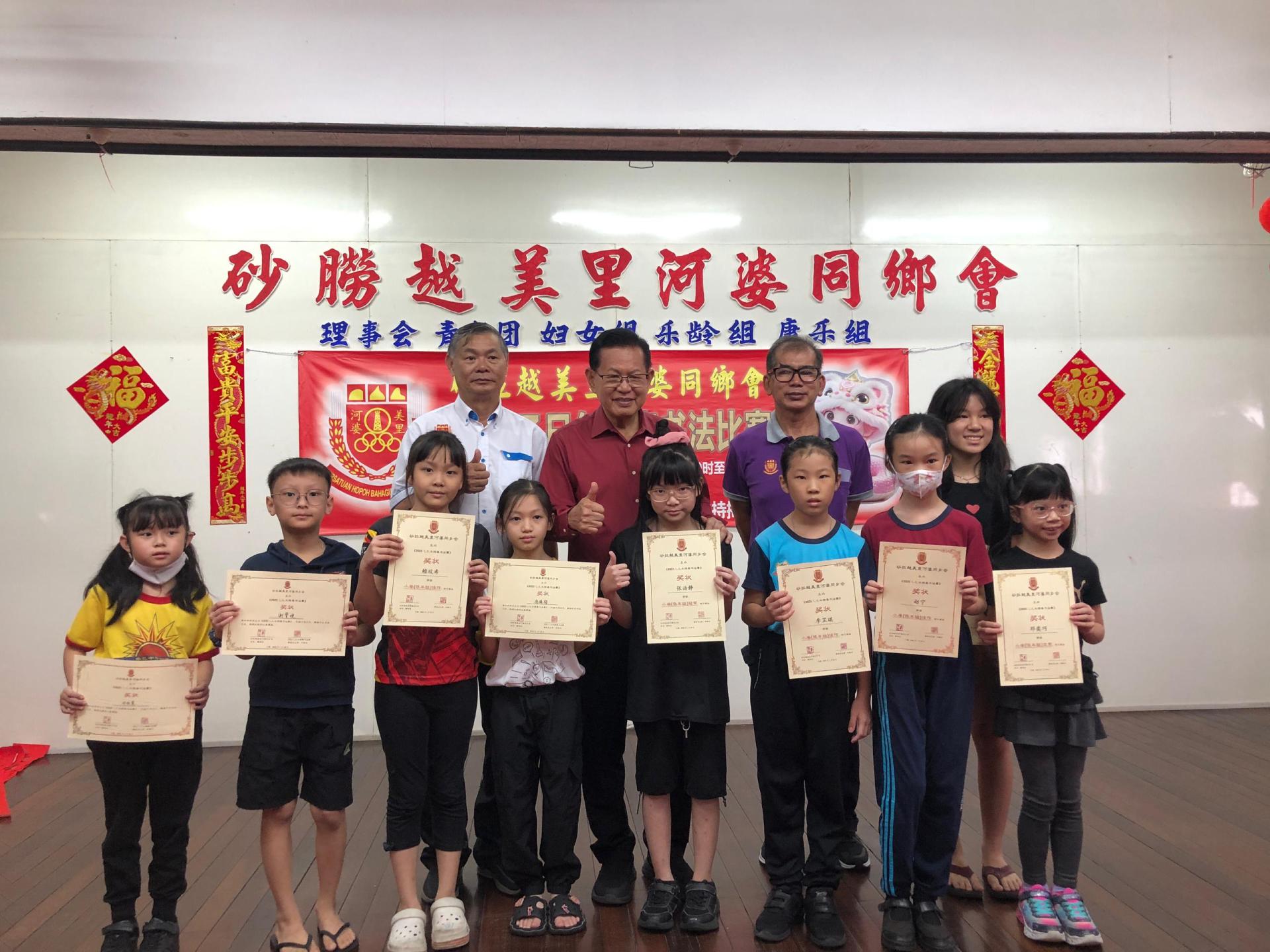 小学低年组得奖者与颁奖嘉宾合影。后排左起为美里河婆同乡会会长蔡传创、主宾砂拉越交通部长拿督斯里李景胜及筹备会主席邓展华。