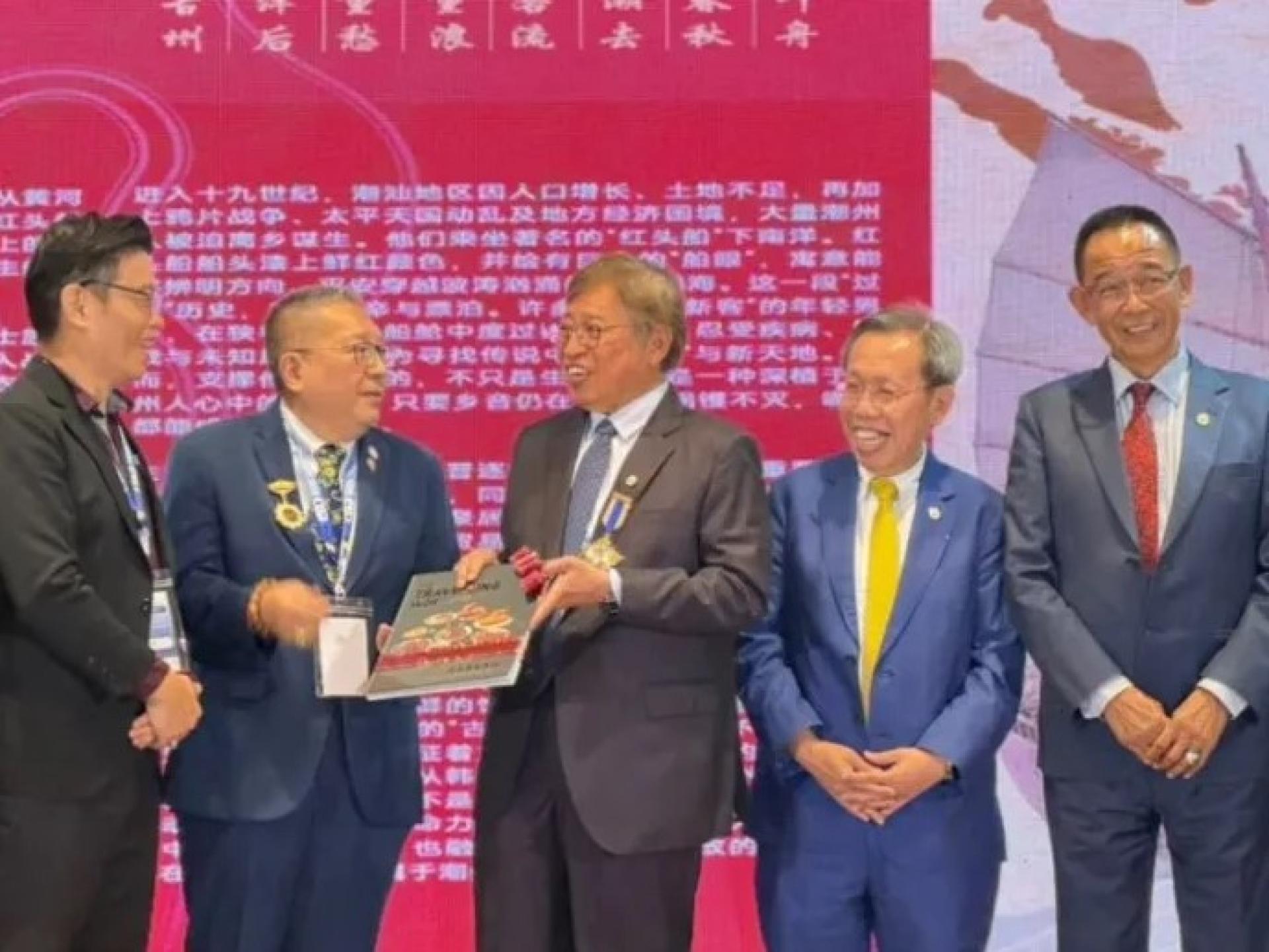 阿邦佐哈里（中）于2026年8月4日在古晋举行的第三届联合国教科文组织创意城市网络美食创意城市年会上，为《The Travelling Wok | Culinary Passage Between Chaozhou & Kuching》新书发布仪式接收书本。