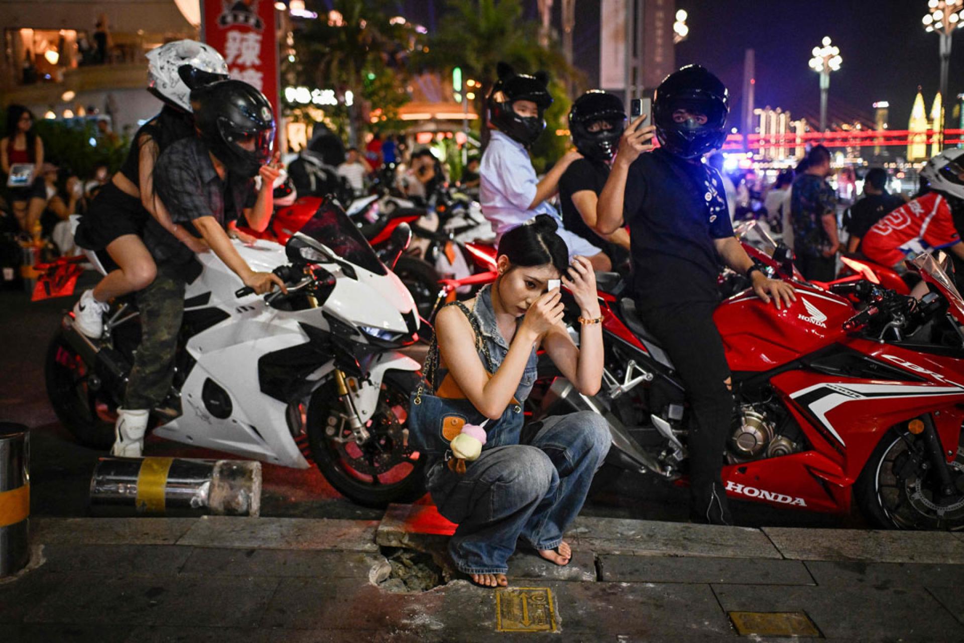 7月20日,重庆一名女游客正在为摩托车骑行拍照和录像做准备。