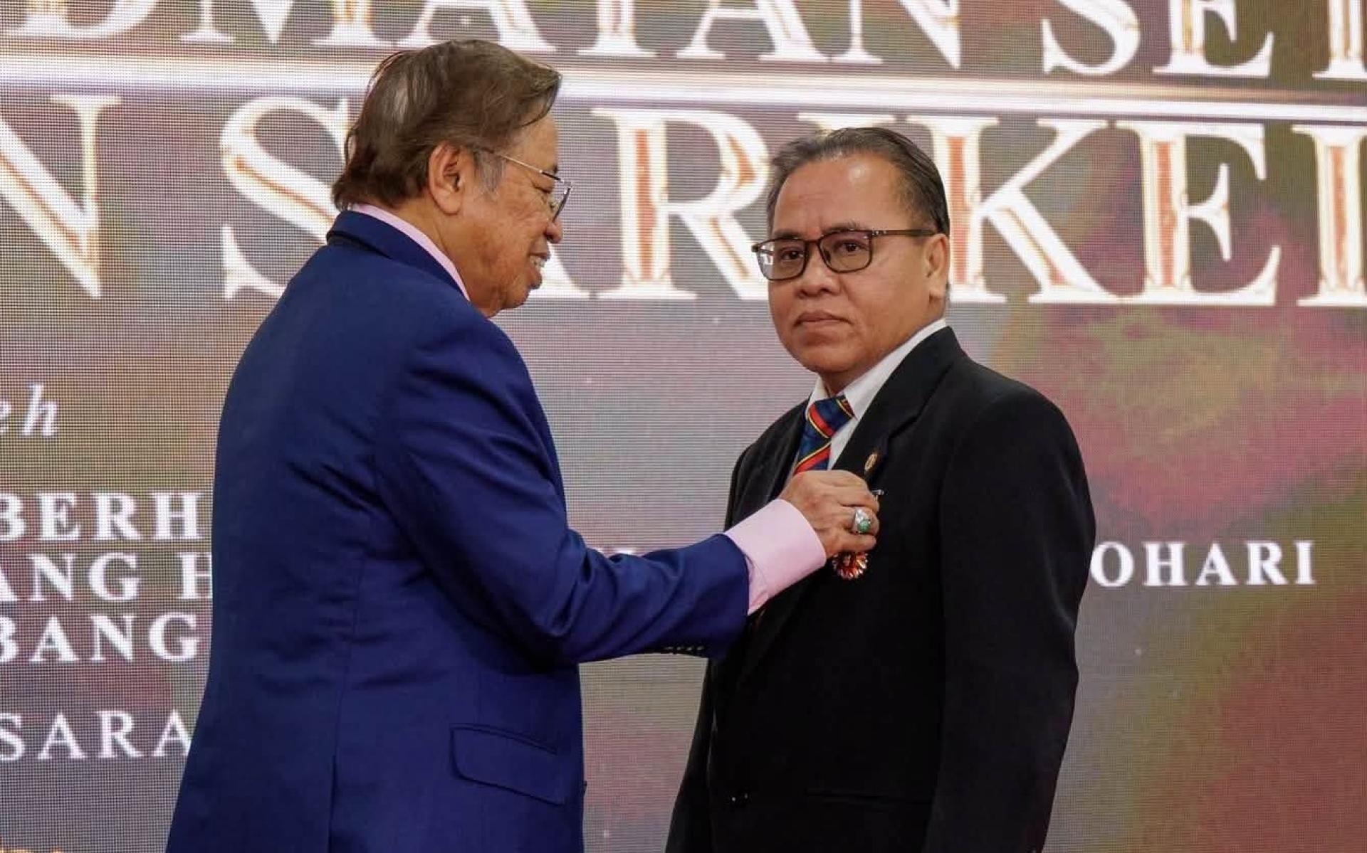 总理阿邦佐哈里（左）颁发服务奖章给其中一名得奖者。