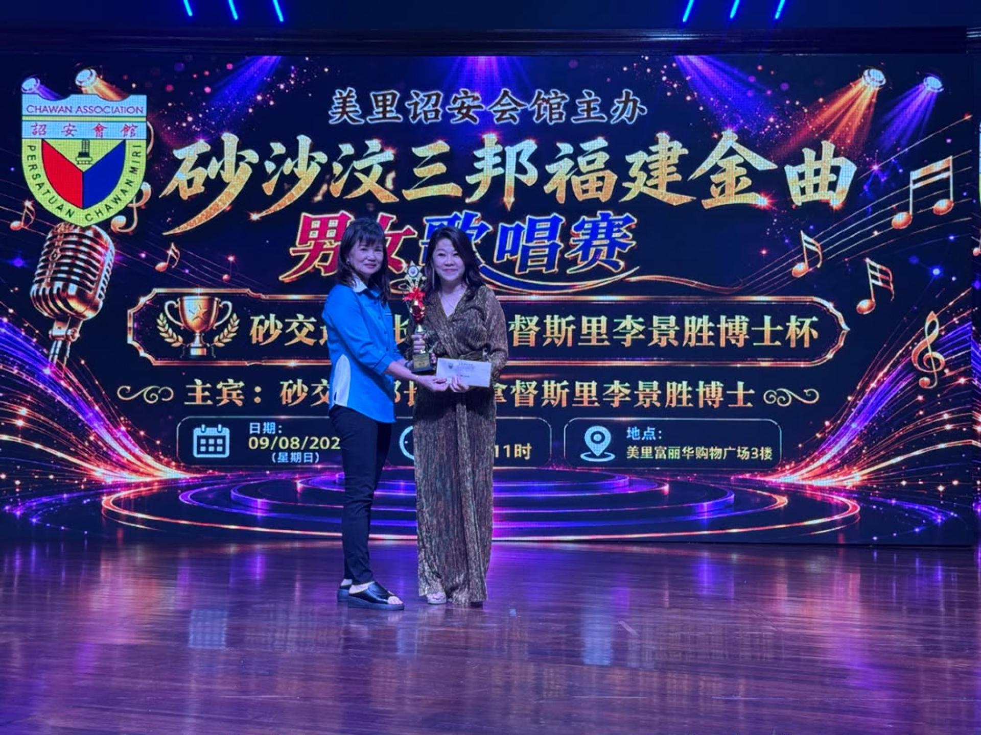 美里诏安会馆会长林美英（左）颁发“砂沙汶三邦福建金曲男女歌唱赛”女子组冠军奖予张晓萍。