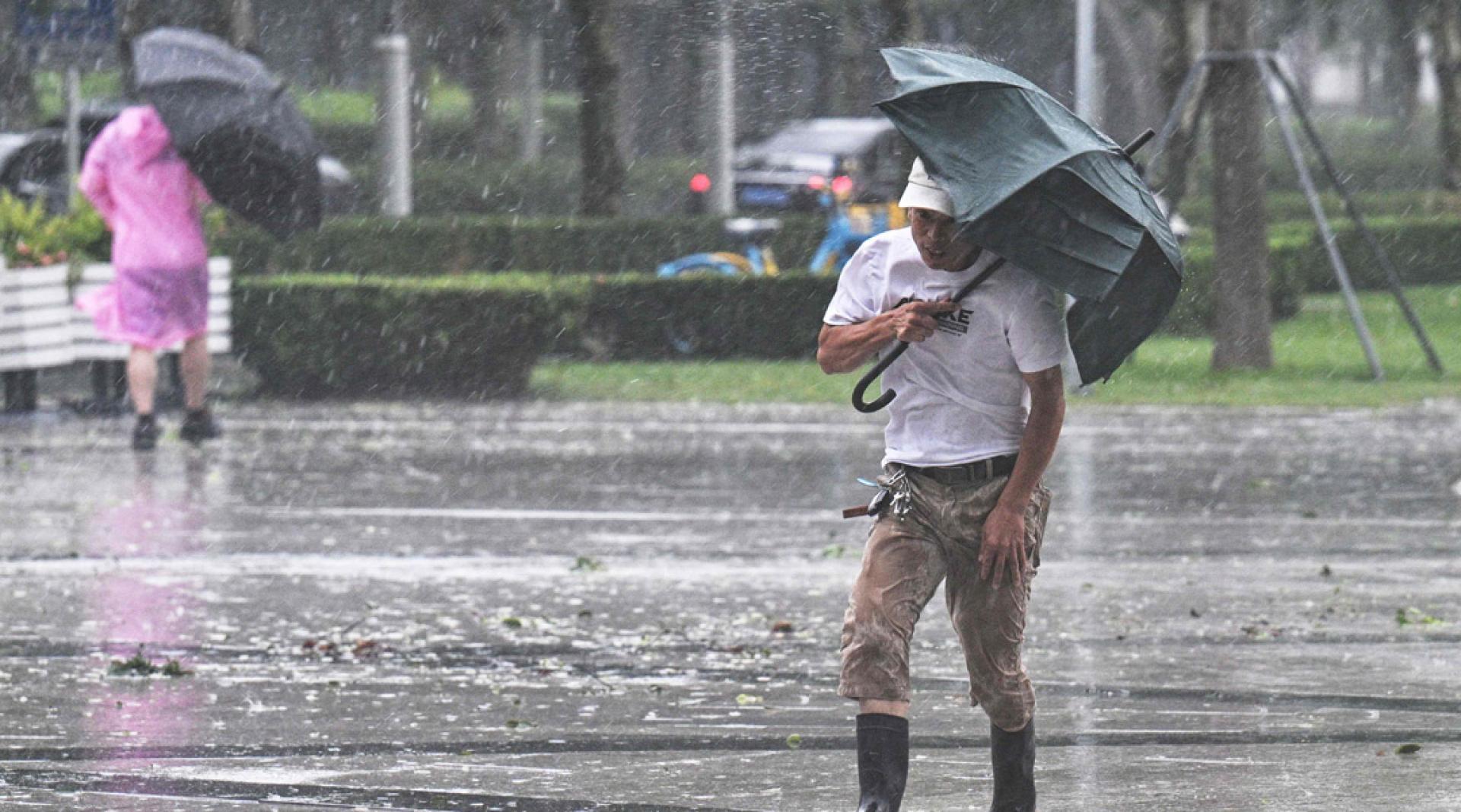 在上海，人们周一在暴风雨中艰难行走。