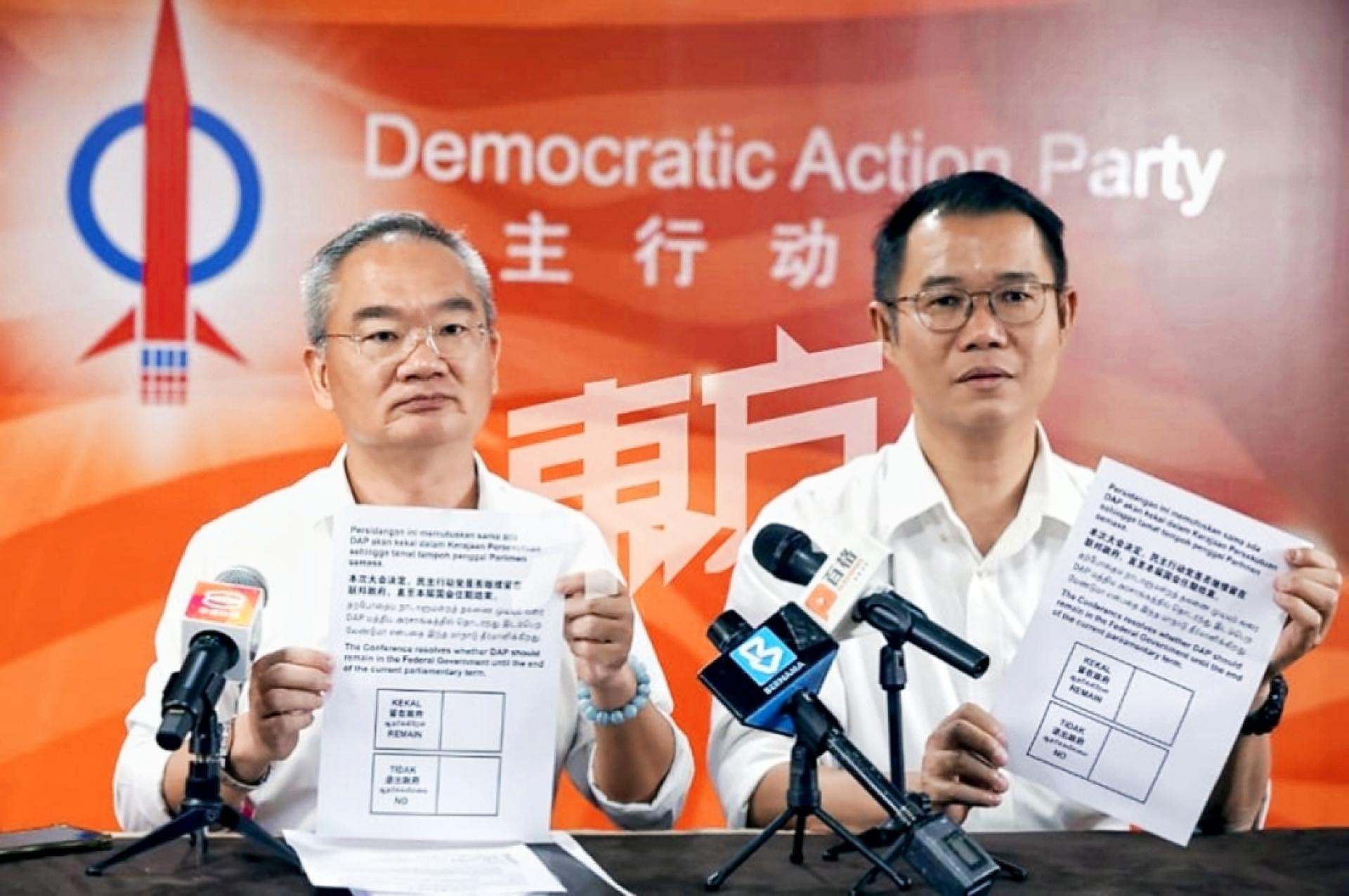 邱培栋和陈泓宾展示选票，代表将决定行动党是否继续留在联邦政府直至本届国会任期届满。