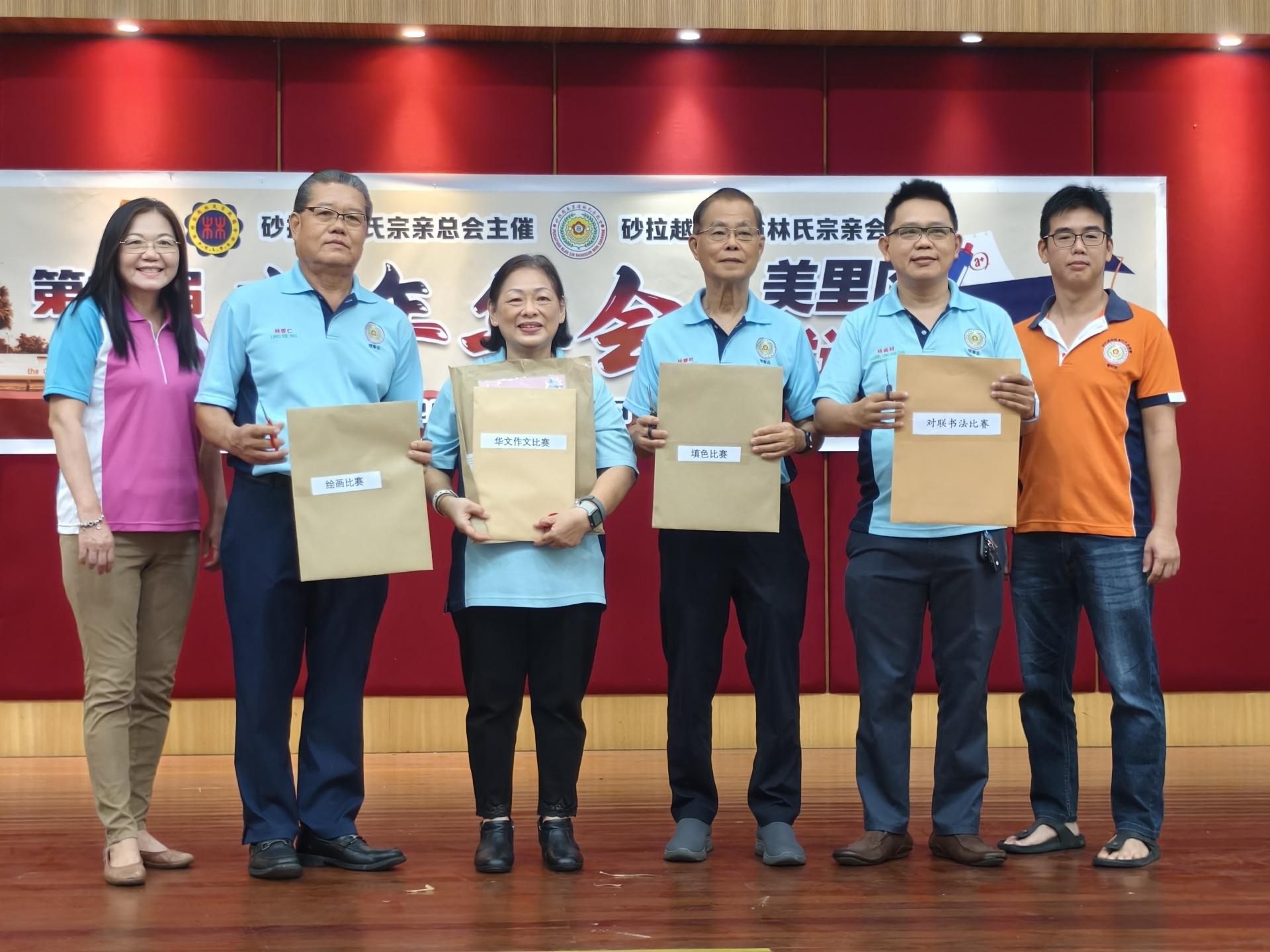 左起为美里省林氏宗亲会妇女组主任林丽、副会长林启仁、会长林淑华、副会长林辉明、教育 主任兼美里区学术选拔赛筹备会主席林咸材，以及青年团团长林兆杰一同展示作文比赛、书法比赛、填色比赛及绘画比赛的密封信封。