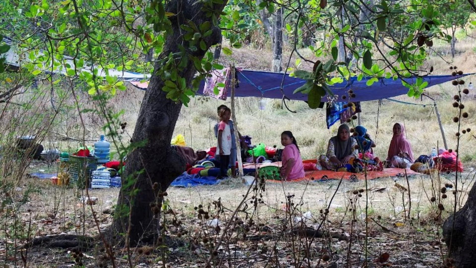 印度尼西亚发生地震后，村民们撤离到山上，坐在临时搭建的帐篷下。