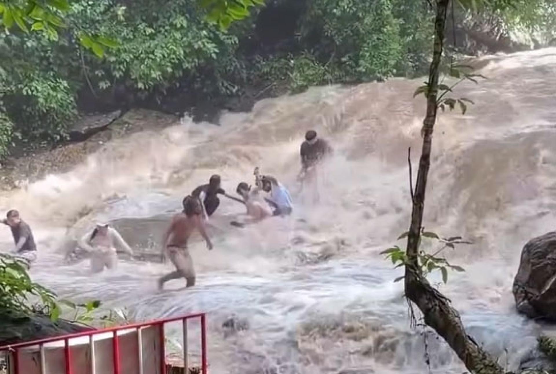 湍急水流突然从上游冲下，导致正在瀑布区域拍照及戏水的游客措手不及，现场一度陷入混乱。（视频截图）
