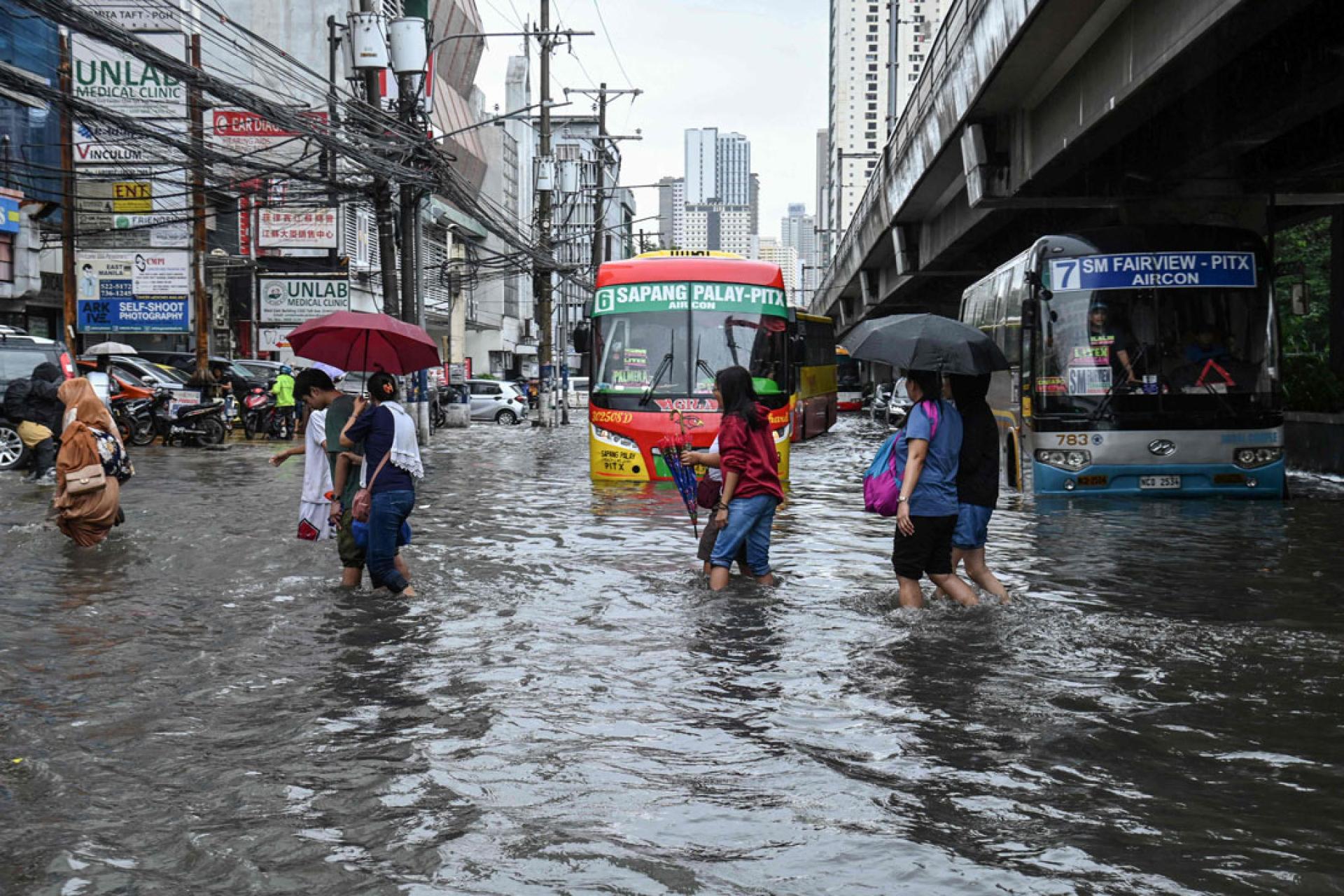 在马尼拉，通勤者穿过积水的街道。