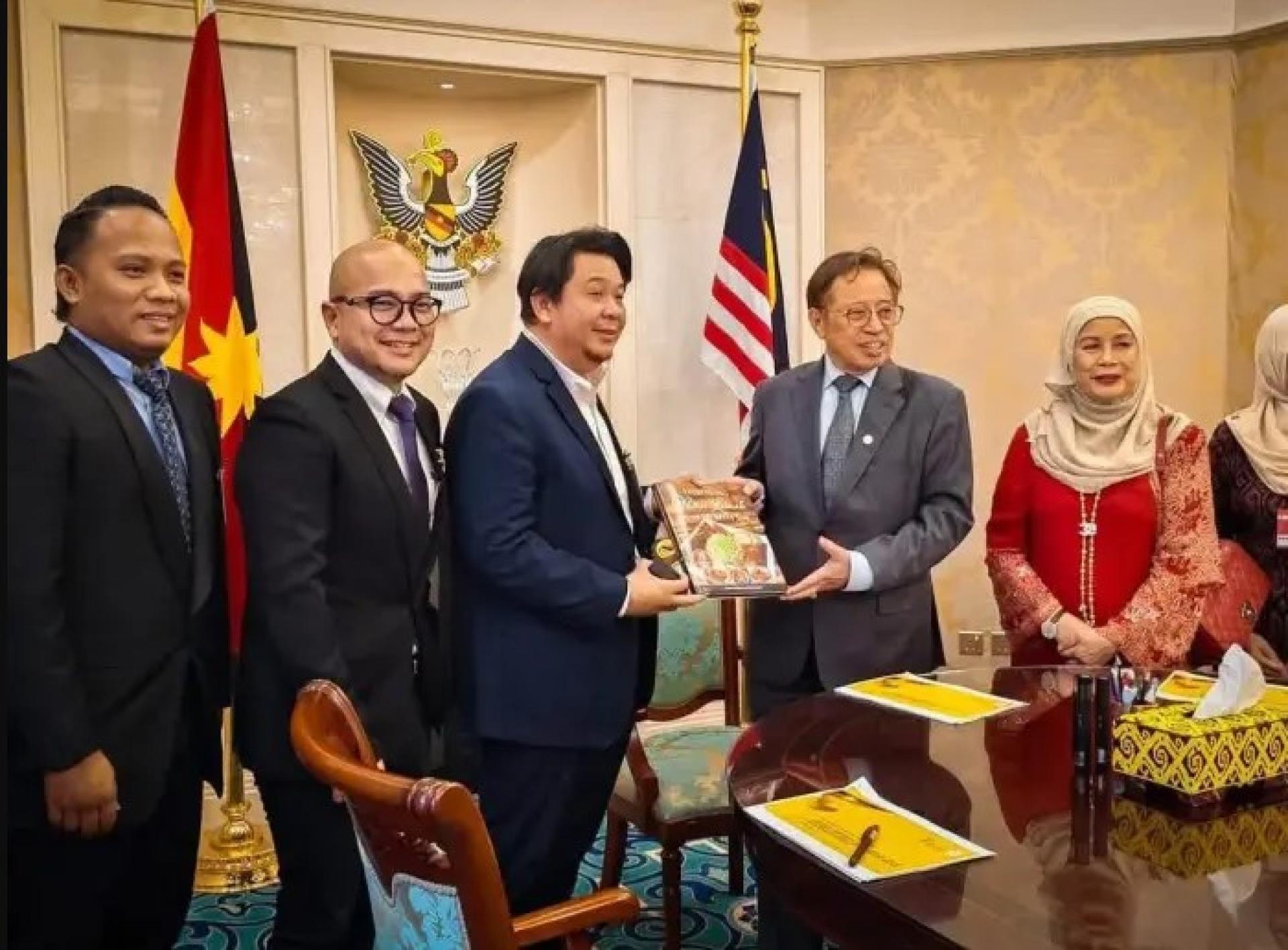 阿邦佐哈里（右2）于2026年8月27日在砂拉越总理办公室，从实务地区国会议员拿督卢卡尼斯曼手中接过书籍。右为嘉米拉，现场还有其他贵宾。图：UKAS
