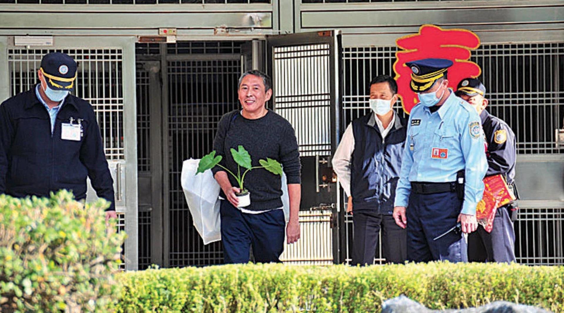 钮承泽开监狱大门时露出笑容，手上捧着自己种的吉安特产槟榔心芋头的盆栽。