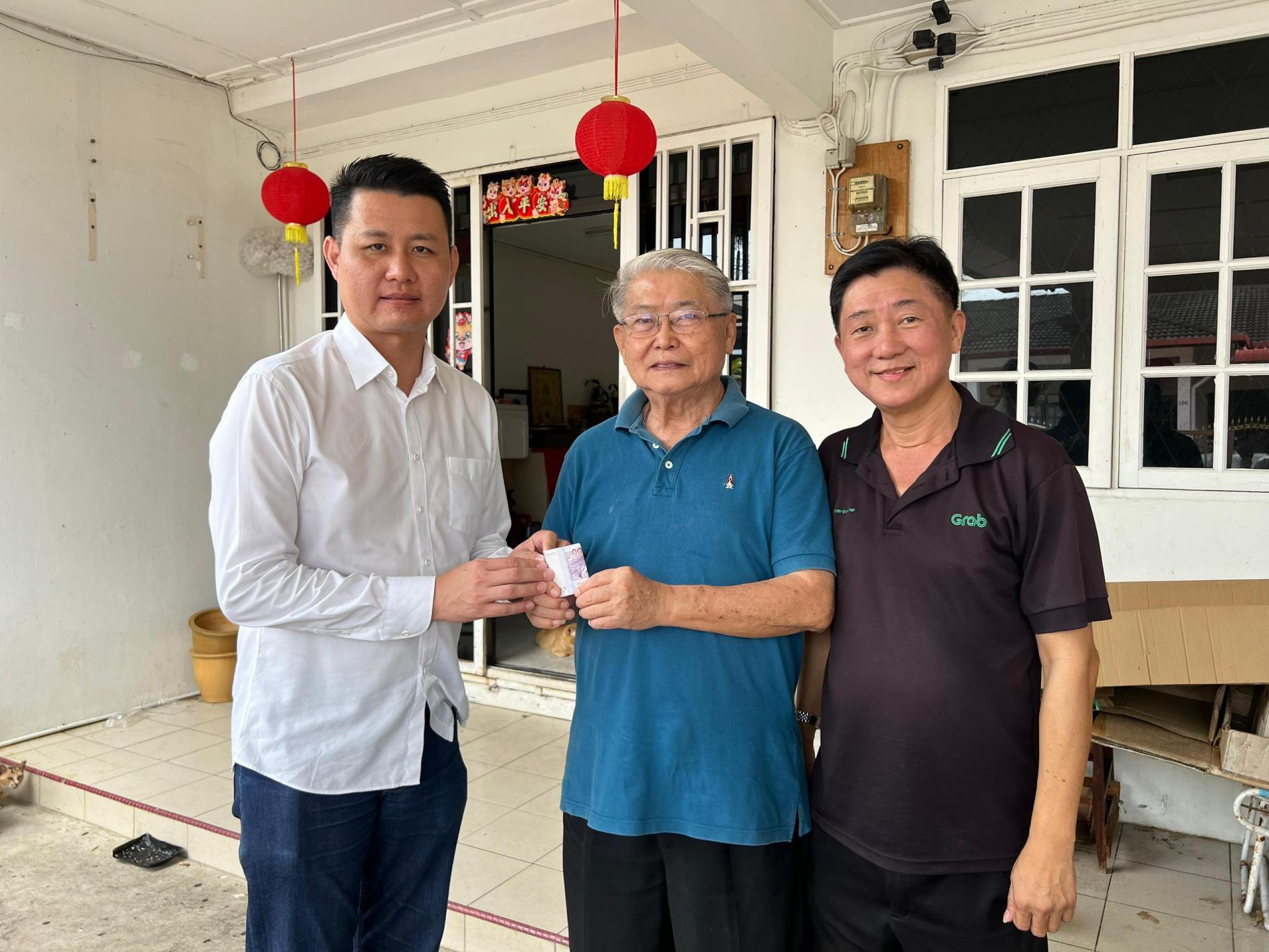 砂希盟兼行动党秘书林思健律师（左）颁发新春援助金给受惠者。