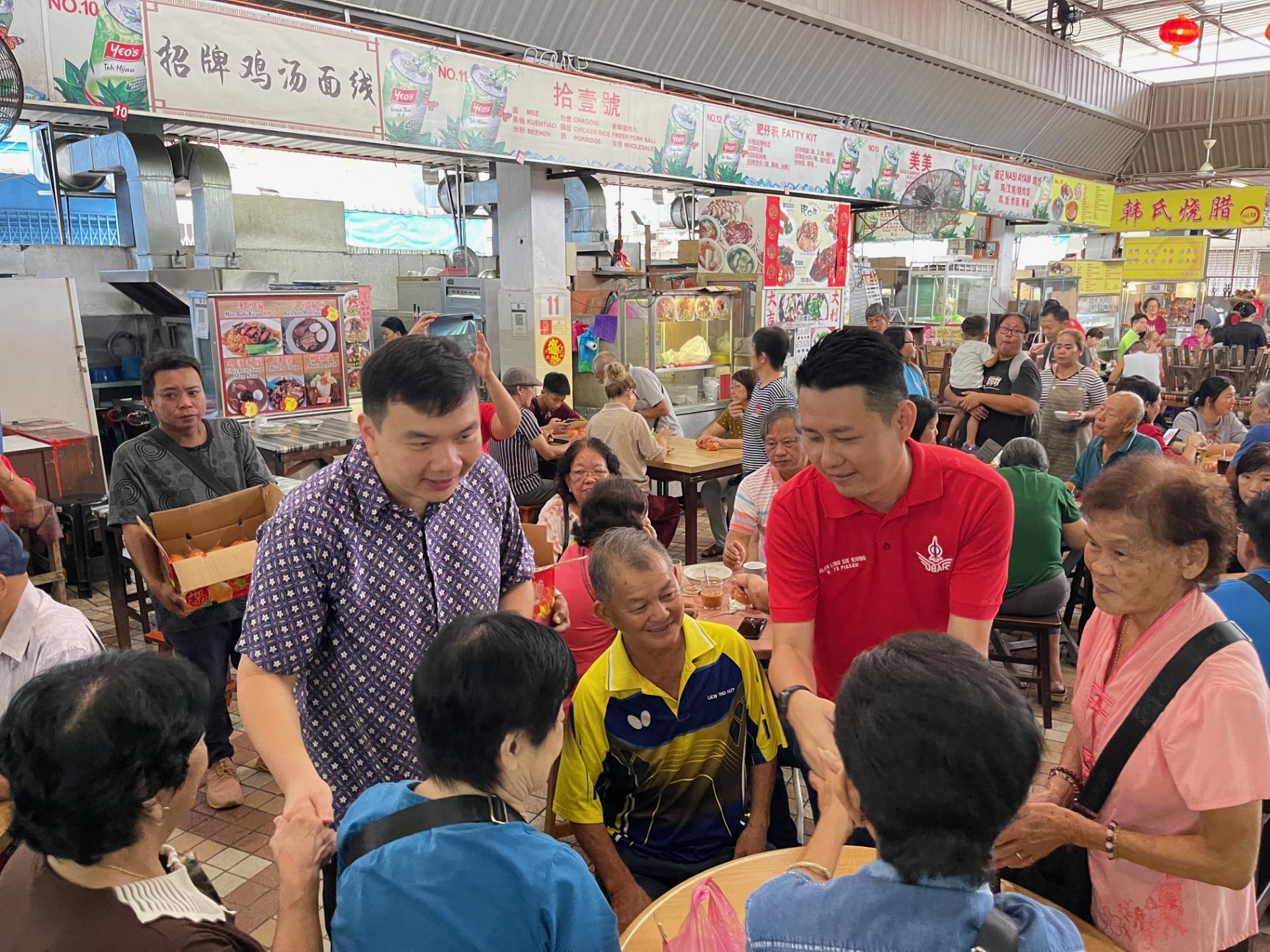 赵俊文（左）和林思健（右）一同在市集向民众贺年。