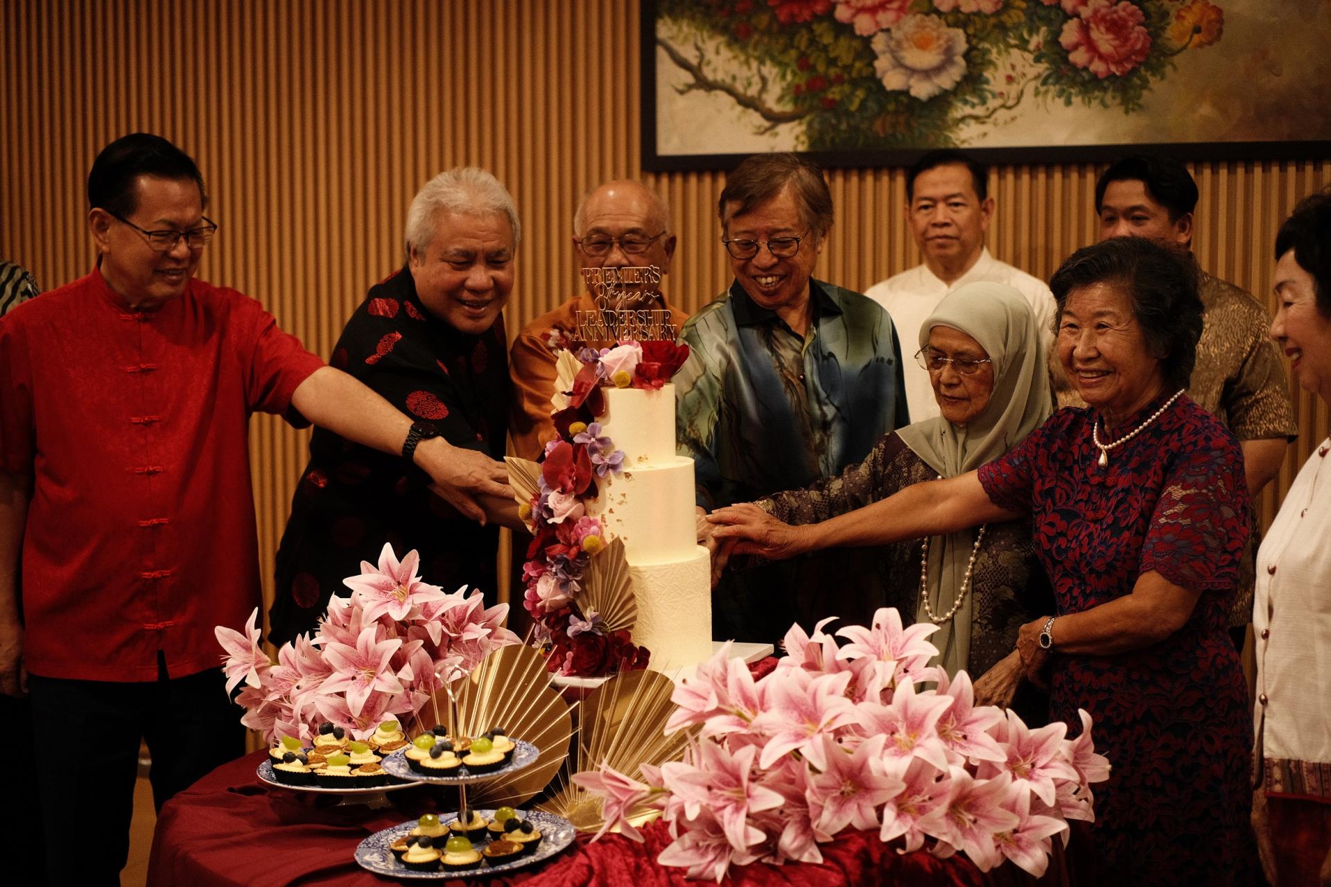 砂总理阿邦佐哈里（左4）与夫人祖玛妮（右3）、钟带友（左3）与夫人赖月春（右2）、副总  理拿督阿玛阿旺登雅（左2）、砂交通部长拿督斯里李景胜（左）与夫人拿汀斯里江淑玲（右）一同切阿邦佐  担任总理8周年蛋糕。